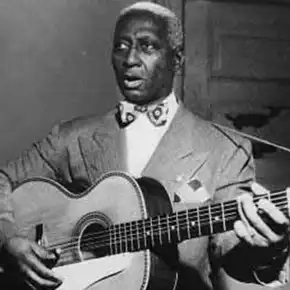 Folk singer Leadbelly holding guitar and singing